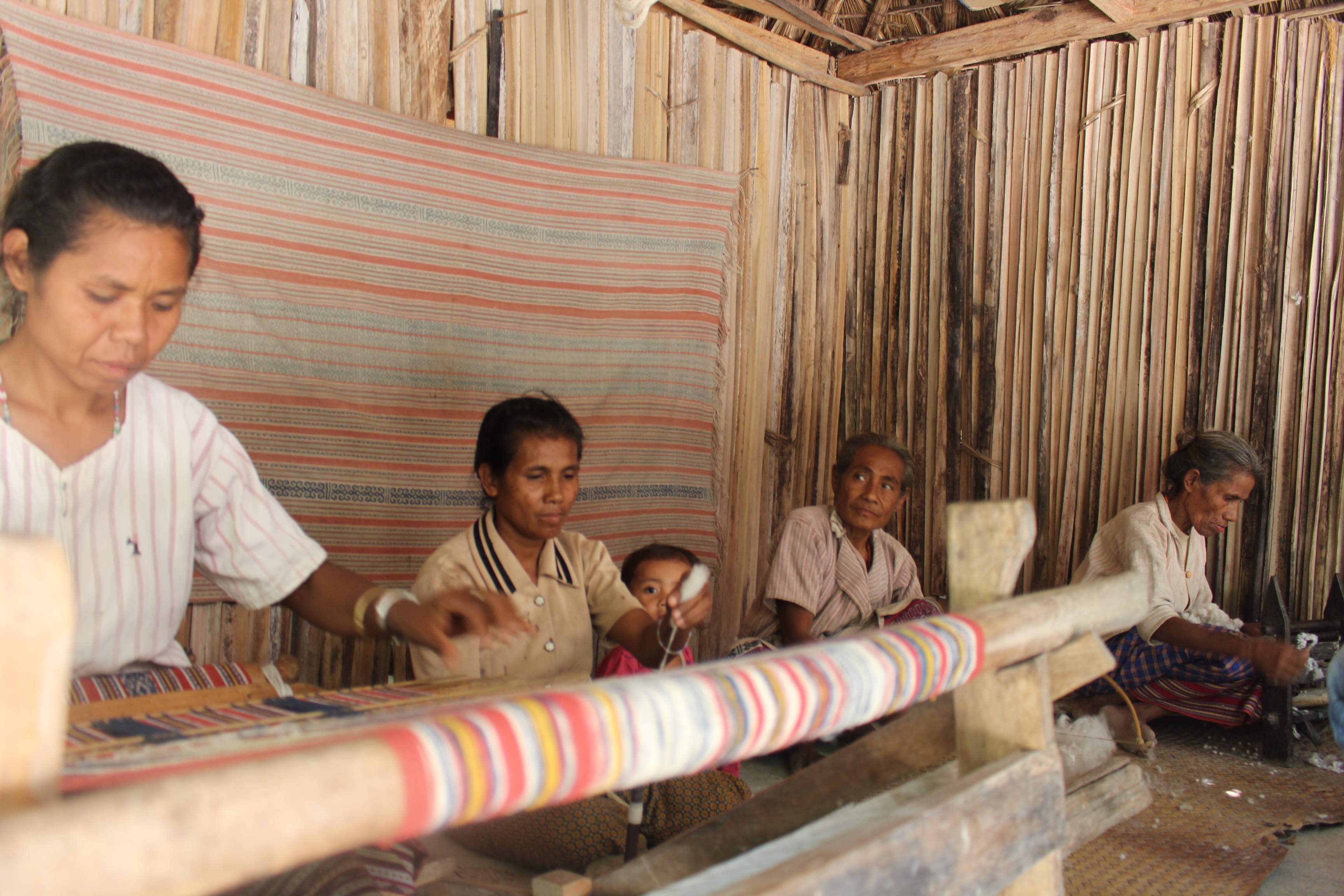 Wanita Timor sedang menenun kain tradisional